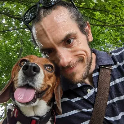John outdoors with a beagle leaning against his shoulder